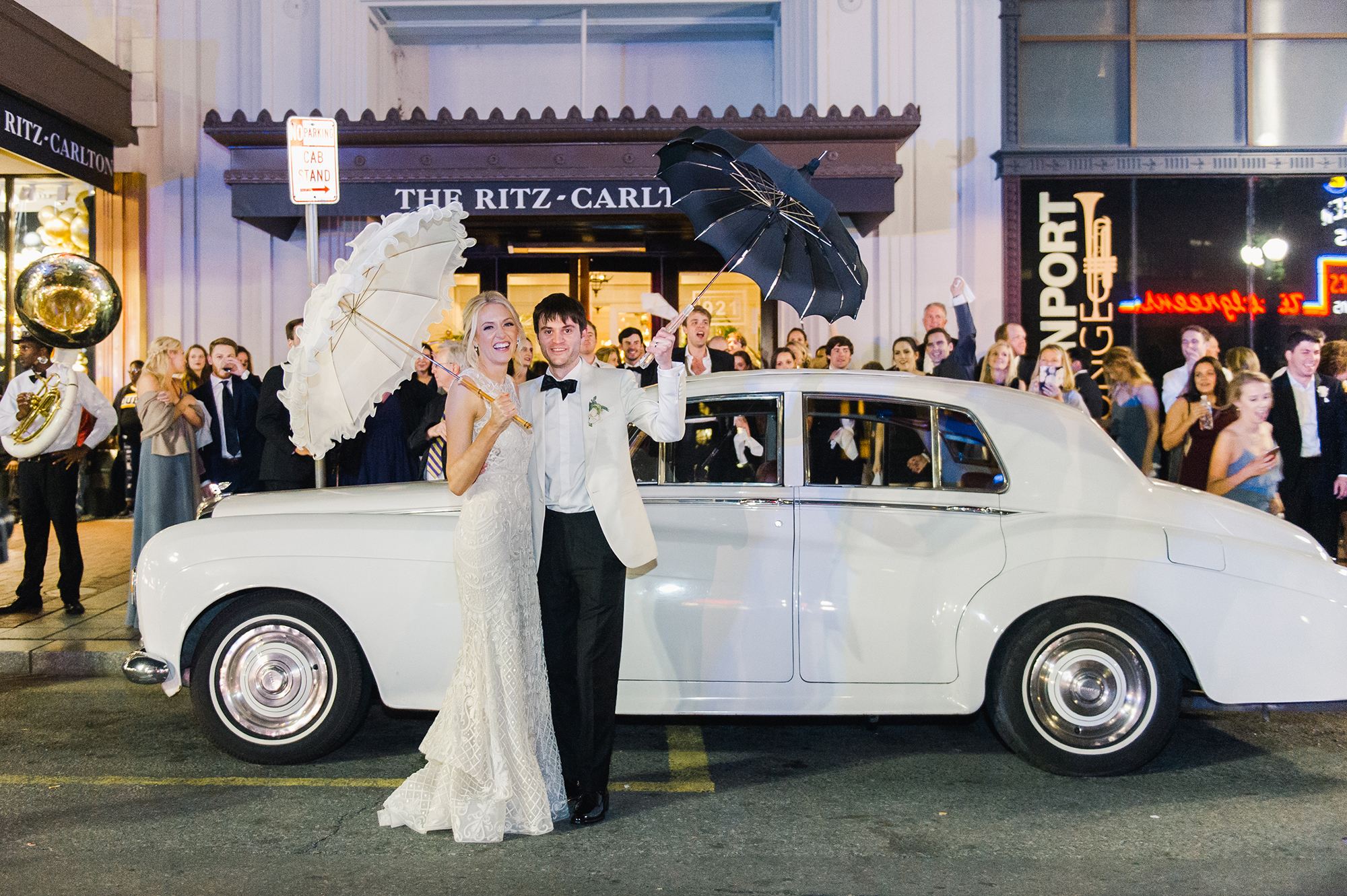 Bride and groom in front of car with parasols