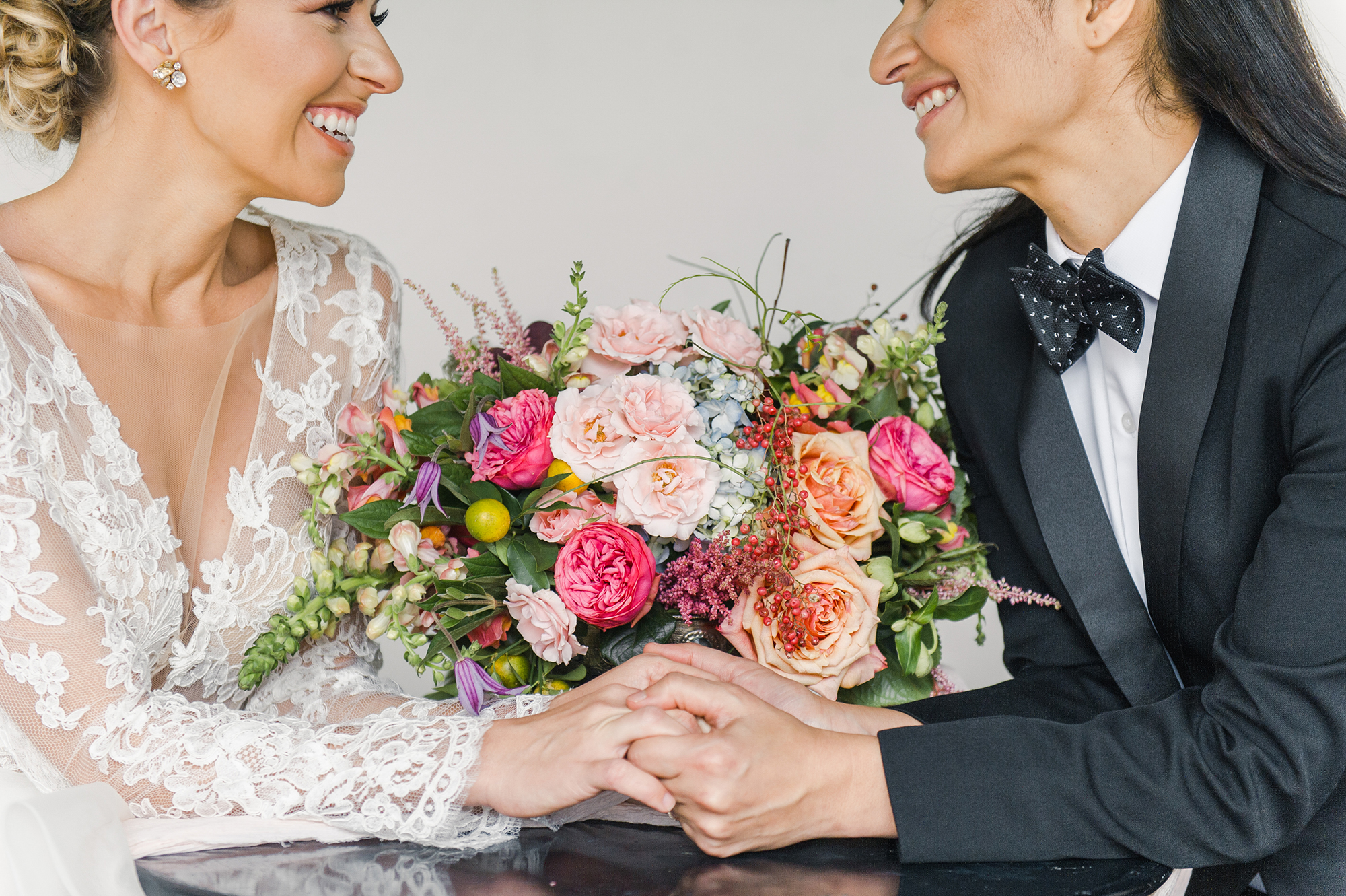 Brides holding hands with floral arrangement