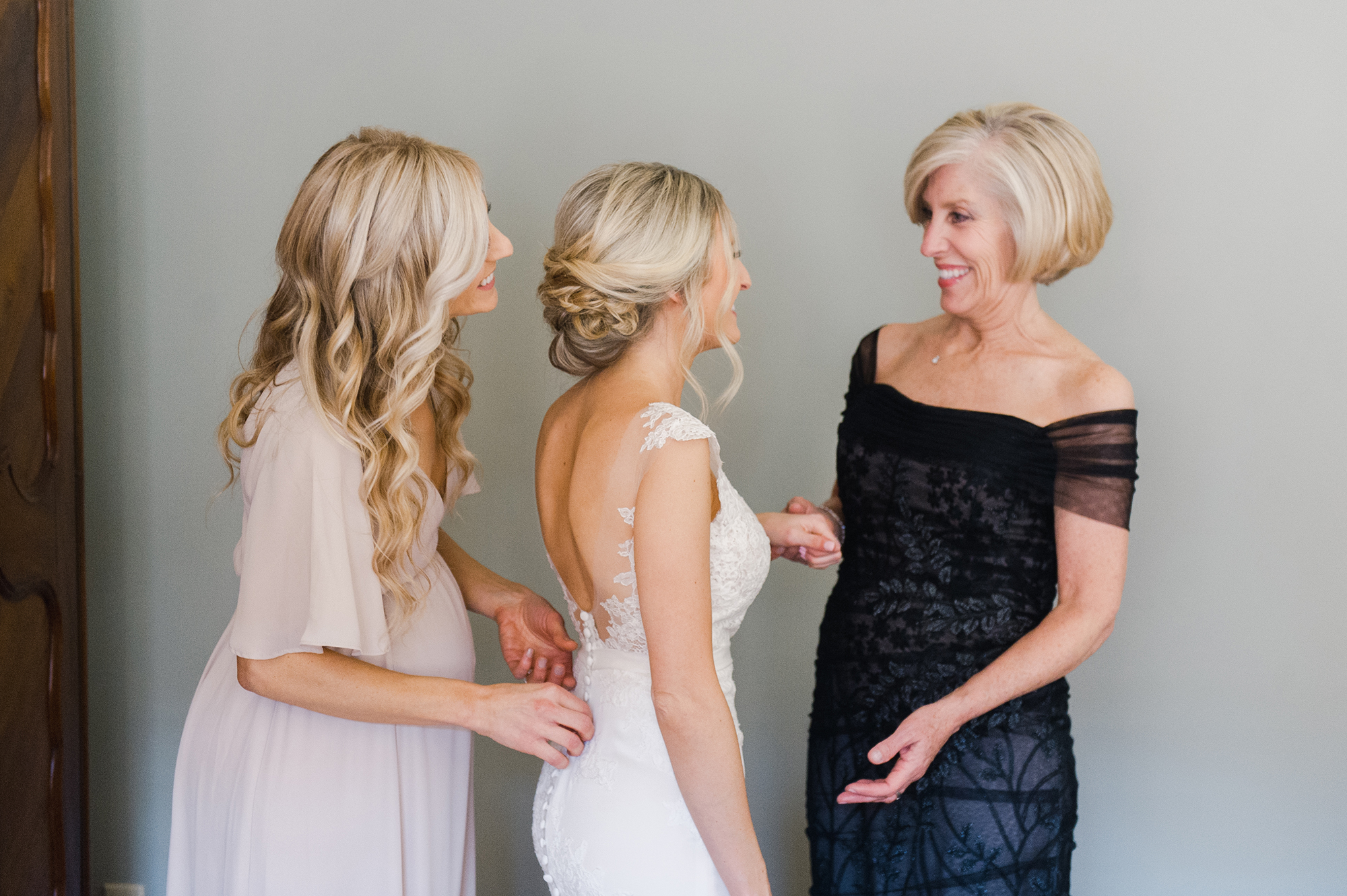  bride getting into wedding dress with mother and bridesmaids