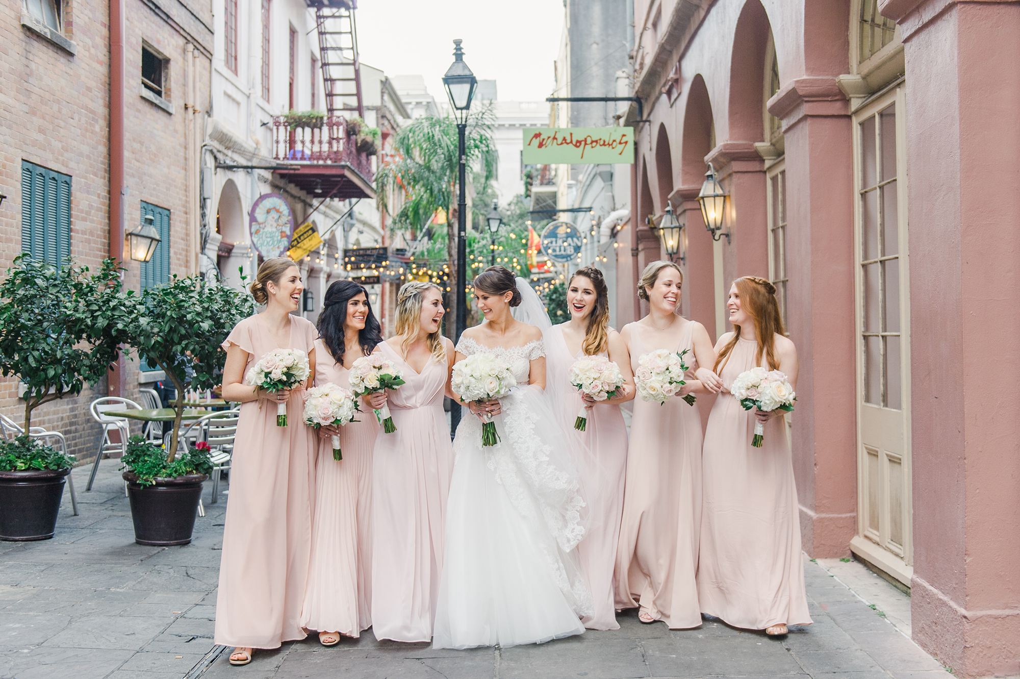 bride with bridesmaids and bouquets walking down the street